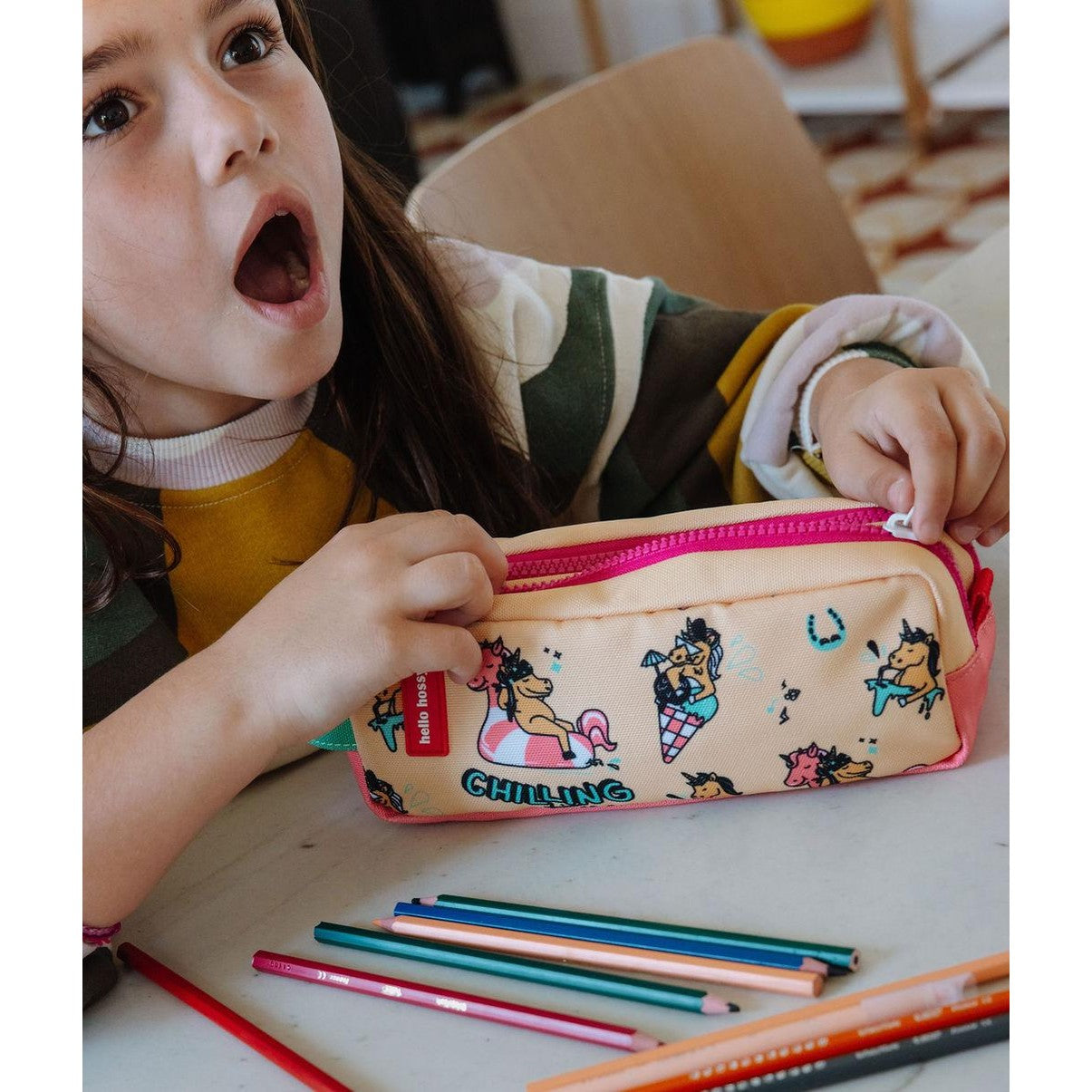 Girl holding beige Hello Hossy unicorn print school pencil case