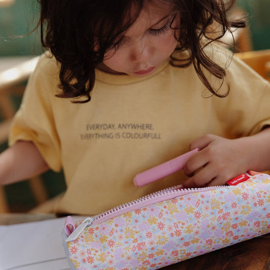 Child using colorful markers with retro flower pattern school pencil case