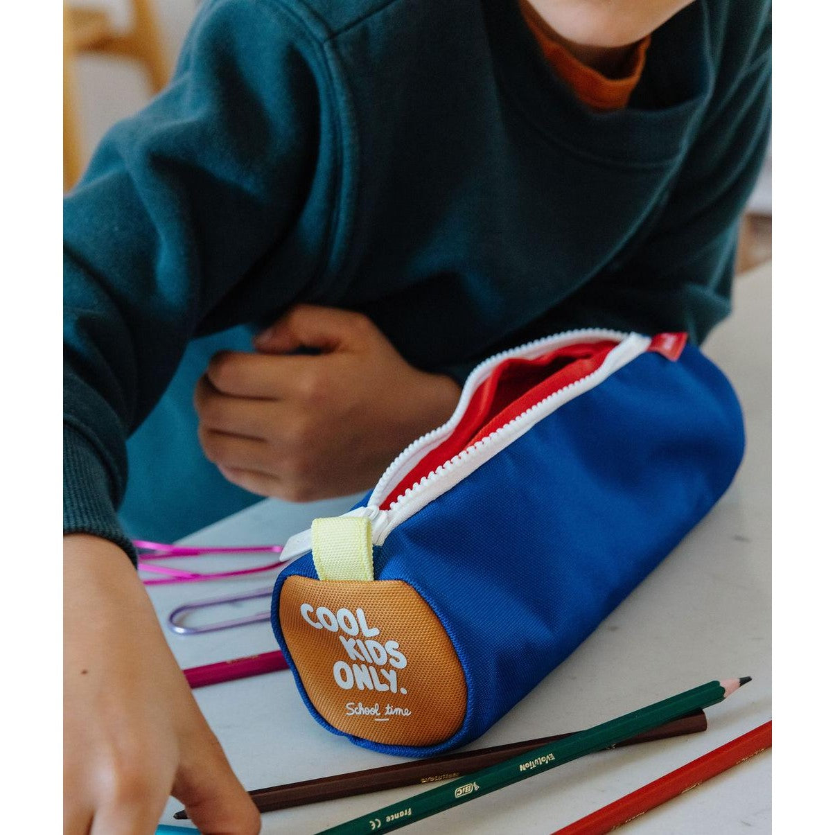 Blue cylindrical kids pencil case with orange COOL KIDS ONLY patch and red interior