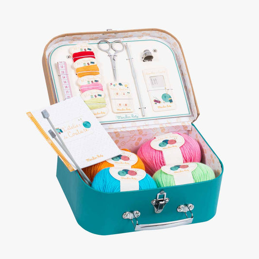 Open teal Moulin Roty sewing suitcase displaying organized craft supplies and yarn