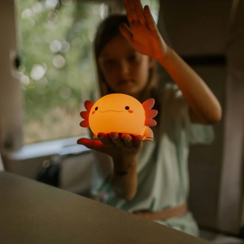 Child holding glowing pink axolotl night light for bedtime