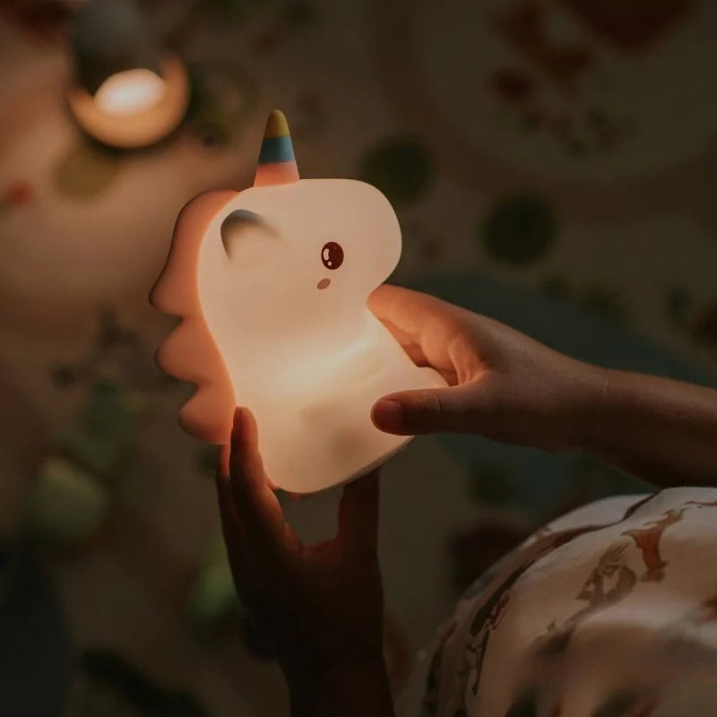 Illuminated unicorn night light emitting warm orange glow through silicone body