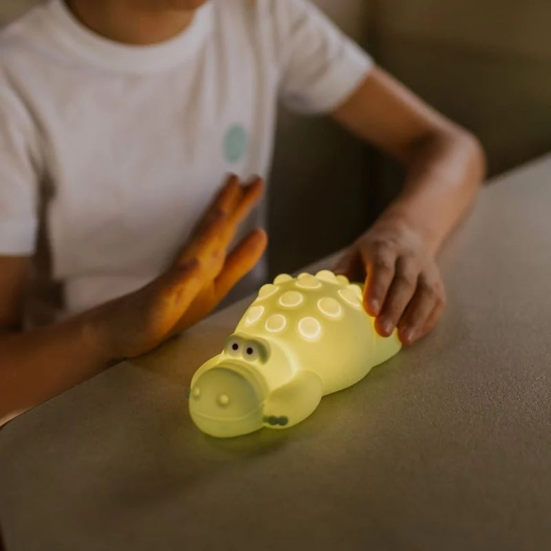 Child playing with glowing green silicone crocodile night light